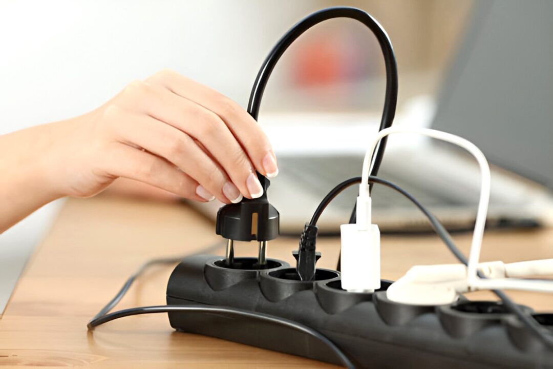 a girl unplugging a laptop charger from socket